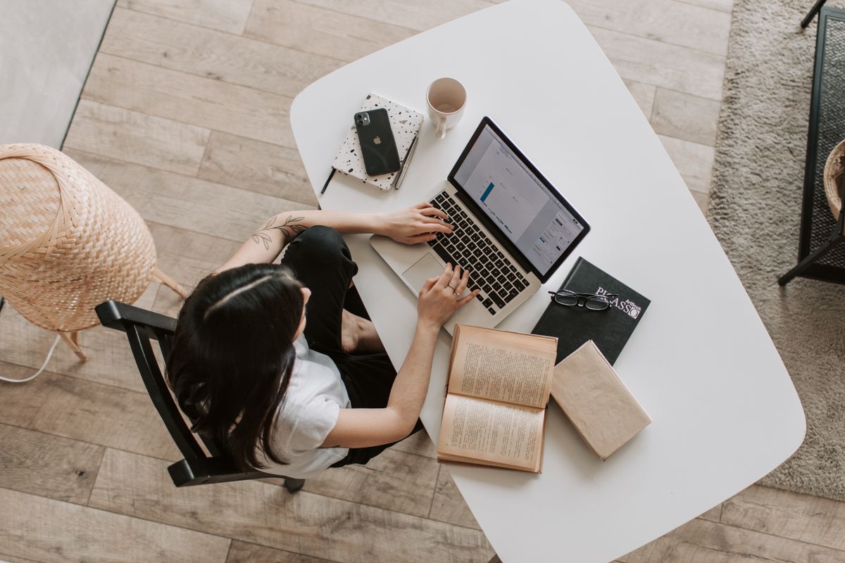 Persona estudiando online con un portátil y libros
